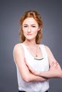 Portrait of a young redhaired beautiful girl in the studio on a gray isolated background. A woman is standing with her Royalty Free Stock Photo