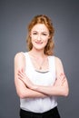 Portrait of a young redhaired beautiful girl in the studio on a gray isolated background. A woman is standing with her Royalty Free Stock Photo