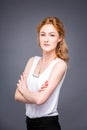 Portrait of a young redhaired beautiful girl in the studio on a gray isolated background. A woman is standing with her Royalty Free Stock Photo