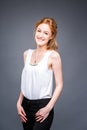 Portrait of a young redhaired beautiful girl in the studio on a gray isolated background. A woman is standing with her Royalty Free Stock Photo