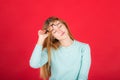 Portrait of a young red-haired beautiful woman of the 20s in a turquoise sweater, will take off glasses with closed eyes, isolated Royalty Free Stock Photo