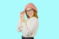 Portrait of a young red-haired girl in a knitted pink hat who is holding glasses with her hand smiling, looking at the Royalty Free Stock Photo