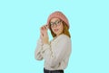 Portrait of a young red-haired girl in a knitted pink hat who is holding a pair of glasses with a serious look is Royalty Free Stock Photo