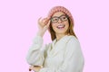 Portrait of a young red-haired girl in a knitted pink hat who lowered her hand with glasses with eyes smiling looking Royalty Free Stock Photo