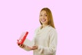 Portrait of a young red-haired girl who is holding an open box and smiling while looking into the camera, isolated Royalty Free Stock Photo