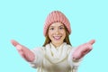 Portrait of a young red-haired teenager girl in a knitted pink hat and knitted pink mittens, arms outstretched to the Royalty Free Stock Photo