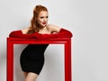 Portrait of young woman artist in black cocktail off-shoulder little tight dress and red elbow-length gloves leaning on Royalty Free Stock Photo
