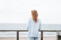 Portrait of young red haired woman in light blue sweater on sand beach by sea in storm Royalty Free Stock Photo