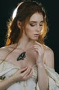 Portrait of a young red-haired woman in a vintage ash dress with open back and shoulders on a black background. A butterfly sits o Royalty Free Stock Photo
