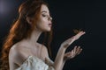 Portrait of a young red-haired woman in a vintage ash dress with open back and shoulders in the moonlight on a black background. S Royalty Free Stock Photo