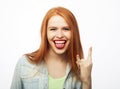 Portrait of young redhair woman looking at camera with smile and showing peace sign with fingers over white background