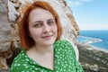 Portrait of young redhead Caucasian woman near cliff above sea in Antalya in spring.