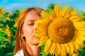 Portrait of young redhead girl with closed eyes hiding her face behind sunflower on a sunny day. Royalty Free Stock Photo