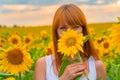 Portrait of young redhead girl hiding her face behind sunflower on sunset. Royalty Free Stock Photo