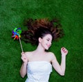 Portrait of a young redhead woman with pinwheel lying down on gr Royalty Free Stock Photo