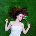 Portrait of a young redhead woman with pinwheel lying down on gr Royalty Free Stock Photo