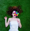 Portrait of a young redhead woman with pinwheel lying down on gr Royalty Free Stock Photo