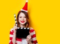 Woman in Santa Claus hat with filmmaking clapperboard