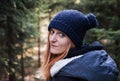 Portrait of young redheaded woman in knitted hat with coniferous forest in background Royalty Free Stock Photo