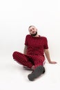 Portrait of young relaxed bearded man with short dark hair wearing red striped sport wear, sitting, leaning on hands.