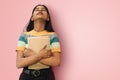Portrait of young relaxed indian asian girl posing tilting head backwards and hugging books expressing positive emotions
