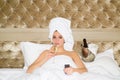 Portrait of young rich sensual beautiful woman watching tv drink champagne on bed. Sexy woman with towel on head Royalty Free Stock Photo