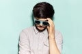 Portrait of young sad guy wearing shades on background of aqua menthe color. Royalty Free Stock Photo
