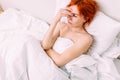 Portrait of a young sad tired woman lying in bed. Illness and headache Royalty Free Stock Photo