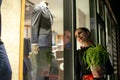 Portrait of a young sad woman standing near a shop window