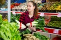 Portrait of a young saleswoman laying out bundles of chinese cabbage on the counter