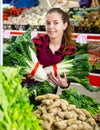 Portrait of a young saleswoman laying out bundles of chinese cabbage on the counter