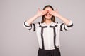 Portrait of young scared woman covering eyes with hands while standing against gray studio background. Confused girl close eyes wi Royalty Free Stock Photo