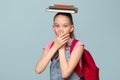 Portrait of a young schoolgirl with books. Cover your mouth with your hands. Copycpase