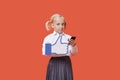 Portrait of a young schoolgirl with cell phone holding fake like button over orange background