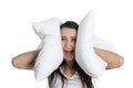 Portrait of young screaming woman covering ears with pillow