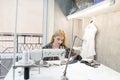 Portrait of a young seamstress at work on a professional sewing machine. Attractive seamstress at work in the studio