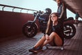 Portrait of a young sensual brunette girl sitting on a skateboard and brutal bearded biker in black leather jacket Royalty Free Stock Photo