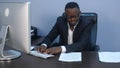 Portrait of young serious afro-american businessman working with laptop and document Royalty Free Stock Photo