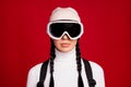 Portrait of young serious attractive beautiful girl skier wear goggles on winter holiday isolated on red color