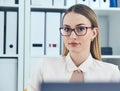 Portrait of young serious businesswoman looking at the camera while using laptop in office. Royalty Free Stock Photo