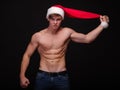 Shirtless Santa in a red hat on a black background. Handsome Christmas guy. New Year party concept. Royalty Free Stock Photo