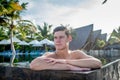 Portrait of young sexy handsome man model relaxing in the swimming pool at the tropical island luxury resort Royalty Free Stock Photo