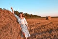 Portrait of young sexy woman on the haystack in morning sunlight, countryside. Beautiful woman in a dress sits on a haystack. Royalty Free Stock Photo