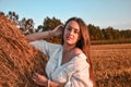 Portrait of young sexy woman on the haystack in morning sunlight, countryside. Beautiful woman in a dress sits on a haystack. Royalty Free Stock Photo