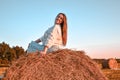 Portrait of young sexy woman on the haystack in morning sunlight, countryside. Beautiful woman in a dress sits on a haystack. Royalty Free Stock Photo