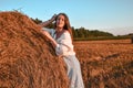 Portrait of young sexy woman on the haystack in morning sunlight, countryside. Beautiful woman in a dress sits on a Royalty Free Stock Photo