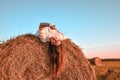 Portrait of young sexy woman on the haystack in morning sunlight, countryside. Beautiful woman in a dress sits on a haystack. Royalty Free Stock Photo