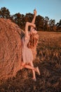 Portrait of young sexy woman with red hair on the haystack in morning sunlight, countryside. Beautiful woman in a dress Royalty Free Stock Photo