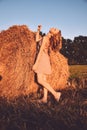 Portrait of young sexy woman with red hair on the haystack in motning sunlight, countryside. Beautiful woman in a dress sits on a Royalty Free Stock Photo