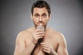 Portrait of a young shirtless man smelling aftershave